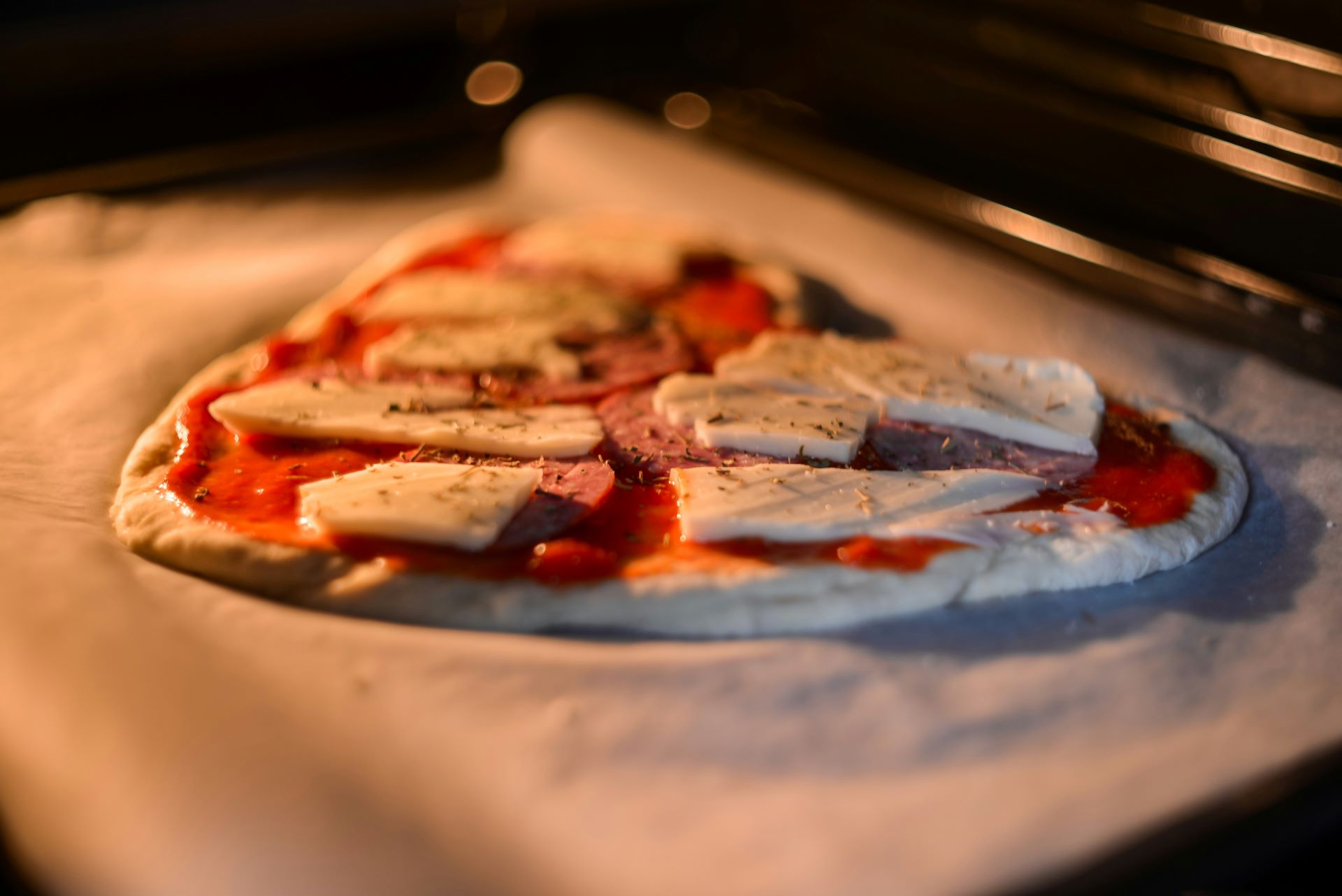 Frisch belegte Pizza mit Tomatensauce, Mozzarella und Salami im Ofen, kurz vor dem Backen, für einen authentischen italienischen Geschmack